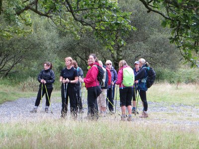 Large group of outdoorsy women on Ramble Worldwide Women's Activity Week holiday standing together on footpath surrounded by trees in the Lake District