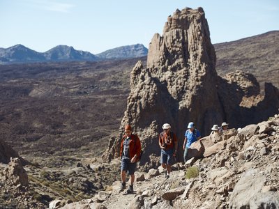 Walking group traversing along rocky path with mountains in background in Teide national park, Tenerife, Spain