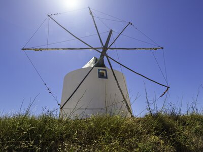 Low angle looking up at Windmill in Odeceixe with sunshining behind in clear blue sky, Portugal