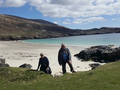 Two people on Ramble Worldwide walking holiday ascending slope away from Hushinish beach in Scotland on sunny day