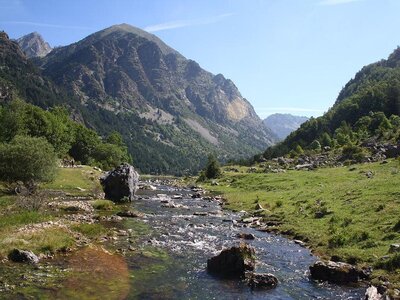 Low river moving towards mountain in distance on sunny day, Aiguestortes National Park, Catalonia, Spain, Europe