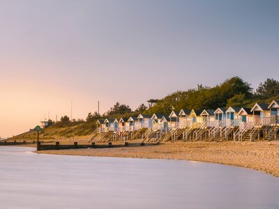 Wells beach huts viewed across a curving beach as the tide comes in