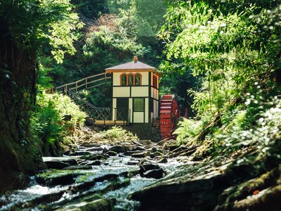Groudle Glen Water Wheel viewed from distance at low angle with sun shining down on sunny day, Douglas, Isle of Man
