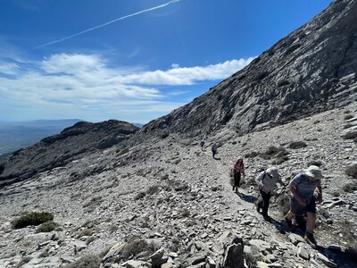 Hikers in a line ascending high rocky mountain pathway on sunny day, Sierra de las Nieves, Andalucia, Spain