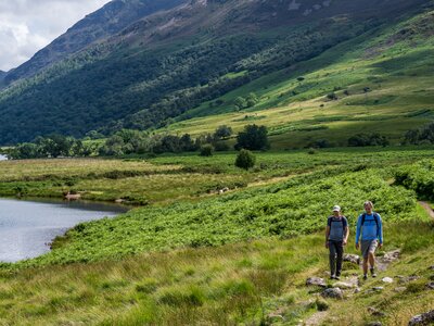 Two men walking in Buttermere Valley near edge of lake, Cockermouth, Lake District