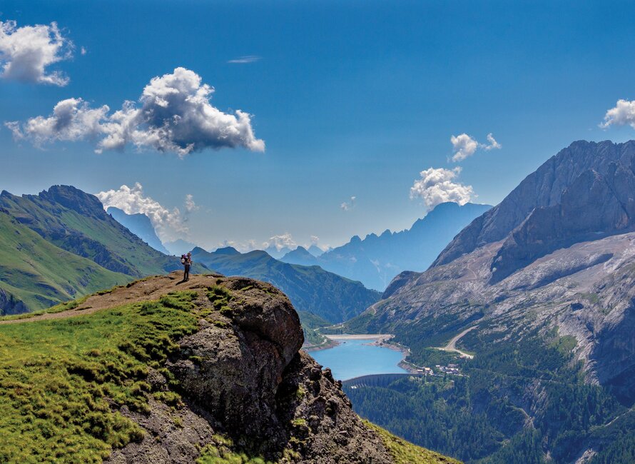Solo walker near edge of cliff face taking in mountainous scenery, Dolomites, Italy, Europe