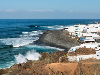 coastal view of El Golfo Village with waves crashing up from the left, Lanzarote, Spain