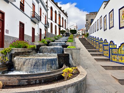Waterfall cascade with colourful artistic chairs with intricate patterns placed along stone stairway in town street, Paseo de Canarias, Firgas Town, Gran Canaria, Spain