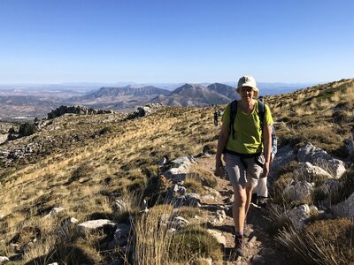 Female walker on rocky dirt trail in high mountains moving towards camera, Sierra de las Nieves, Andalucia, Spain