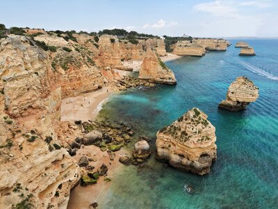 Coastal view of Western coast of Algarve with speedboat passing around large rocks, Portugal