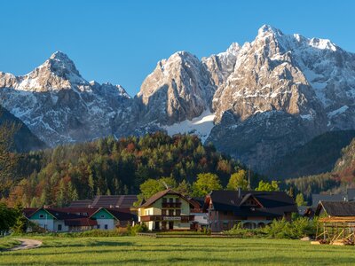 Kranjska Gora village at sunrise with sun highlighting snow-capped mountains in background, Slovenia