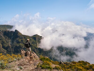 Male hiker on Pico Ruivo trail at cliff edge overlooking mountain range, Madeira, Portugal