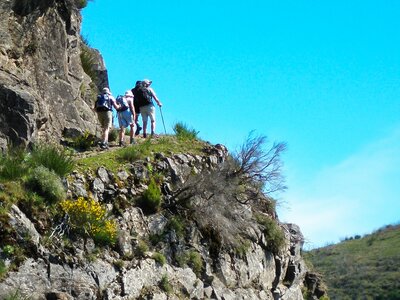Three hikers in Madeira ascending hill near cliff edge, Portugal