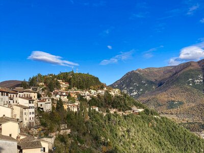 Town of Cerreto di spoleto nestled atop green mountain with mountain in background, Perugia, Umbria, Italy