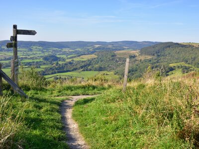 The Cleveland Way walking trail at Sutton Bank in the North York Moors with wooden signpost and background of expansive green countryside landscape