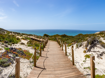 Boardwalk leading to beach on sunny day with clear blue sky, Alentejo, coast of Portugal