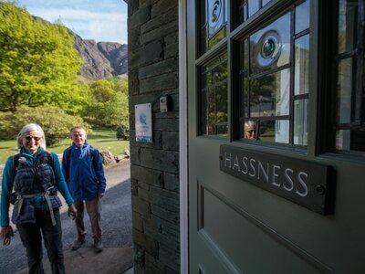 Walkers smiling by front door of Hassness House, Lake District
