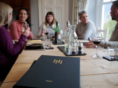 Focus on Hassness House Menu with full table of people surrounding