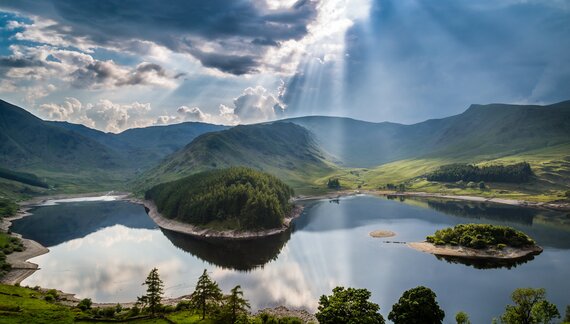Rays of sunshine bursting through dark clouds above Harter Fell and Haweswater in the Lake District, England
