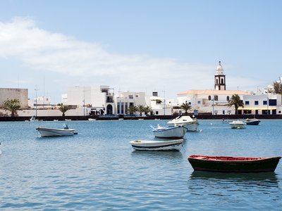 Small boats floating on water with Charco de San Gines in background, the laguna at the city of Arrecife, capital of Lanzarote, Canary Islands, Spain