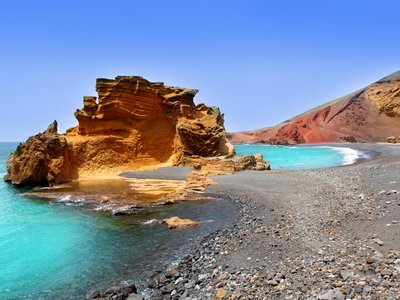 El Golfo Atlantic turquoise ocean with large orange rock near Lago de los Clicos in Lanzarote, Canary Islands, Spain