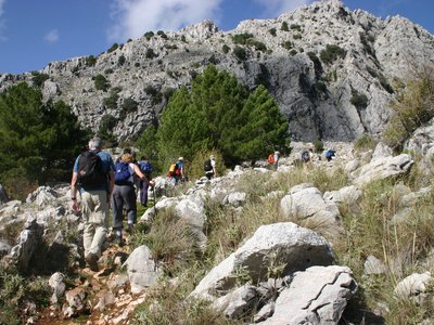 Group of hikers ascending curved rocky path up mountain in Sierra de Grazalema, Spain