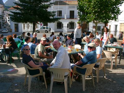 Walking group smiling and enjoying a cool beverage at outdoor cafe in Sierra de Grazalema on sunny day, Spain