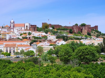 View of castle and cathedral with houses surrounding on hill, Silves, Algarve, Portugal