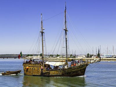 Traditional ship sailing through calm waters near port in Portimao, Algarve, Portugal