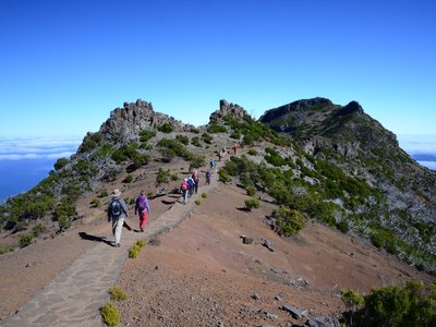 Line of people walking along paved stone path mountain ridge in Madeira, Portugal