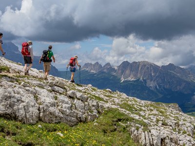 Group of walkers descending a ridge with the Dolomites in the background, Italy